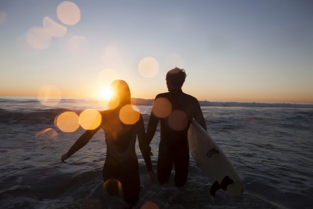 Man and woman in the ocean at sunset