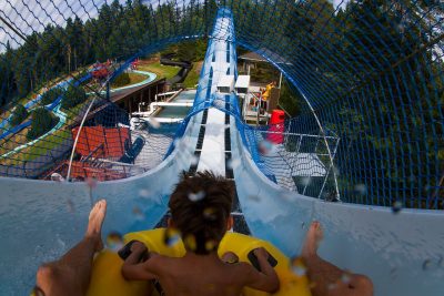 En gutt som sitter øverst i en vannsklie. En dag i sommerland i bø er en av mange opplevelser i Norge for barn hos YouWish.no.
