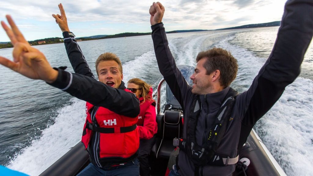 En gjeng med venner som har hendene i været på båttur på Oslofjorden. Ting å gjøre i Oslo om sommeren.