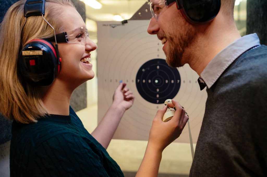 Par som har sjekker skudd på en målskive og smiler mot hverandre. Kjærestetur sommer 2017