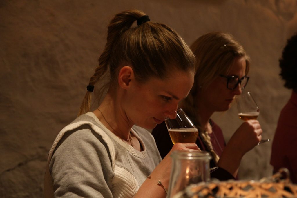 En ung dame som lukter på øl. Bli med på ølsmaking i Oslo.